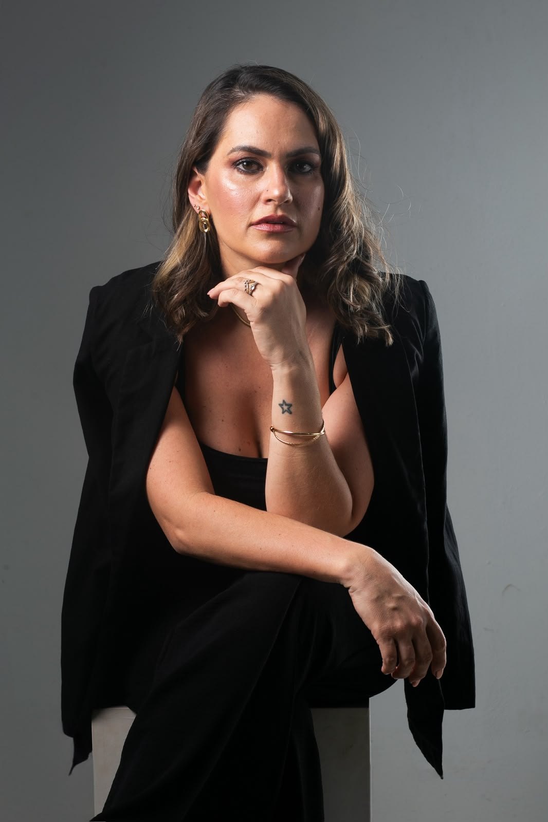 Dra. Fernanda Vilas Boas, de blazer preto, com a mão no queixo