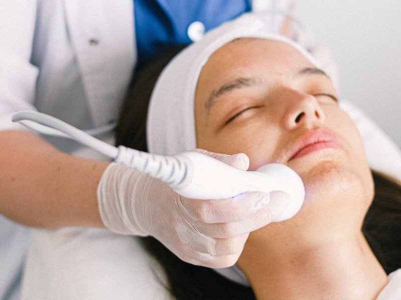 Esteticista aplicando radiofrequência no rosto da paciente